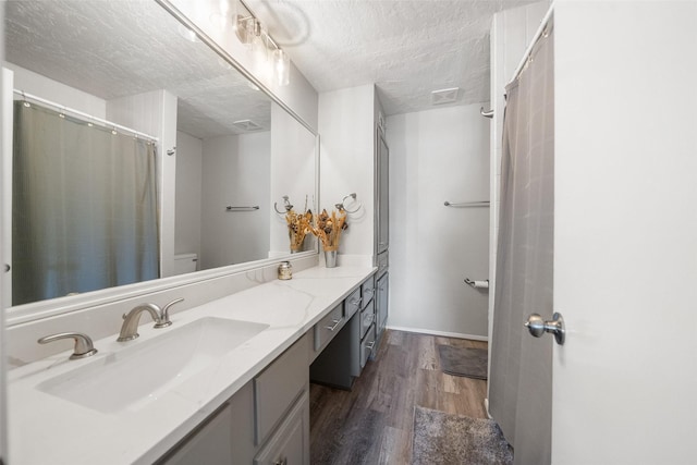1924 Clipper Ct, Willis, TX 77318 - full bathroom featuring wood finished floors, a textured ceiling, vanity, and toilet