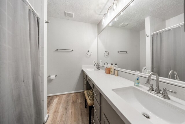 1924 Clipper Ct, Willis, TX 77318 - bathroom featuring a textured ceiling, wood finished floors, baseboards, double vanity, and curtained shower