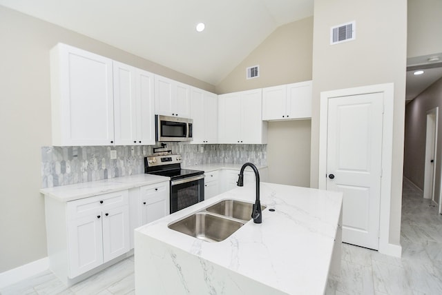 kitchen featuring stainless steel appliances, a sink, light marble finish flooring, light stone countertops, and white cabinetry