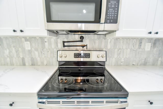 kitchen with appliances with stainless steel finishes, white cabinetry, and tasteful backsplash