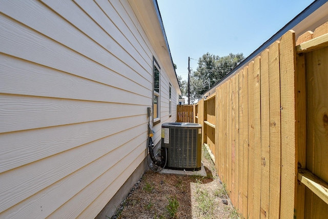 view of side of home with central AC and fence