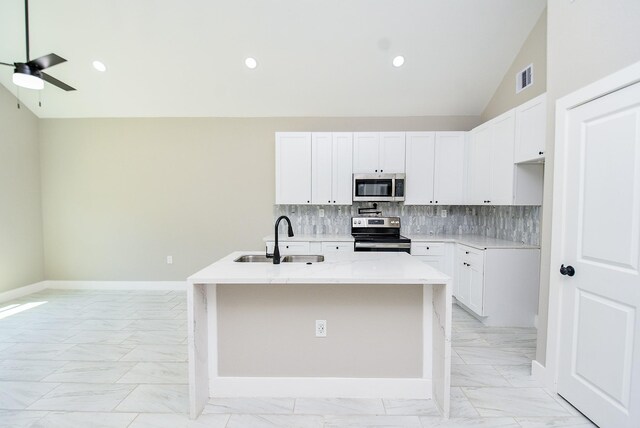 kitchen featuring stainless steel appliances, a sink, light marble finish floors, a ceiling fan, and an island with sink