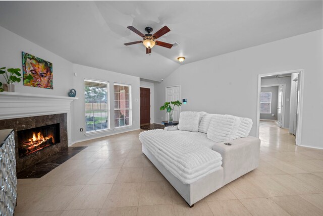 living room featuring healthy amount of natural light, ceiling fan, lofted ceiling, a high end fireplace, and light tile patterned flooring