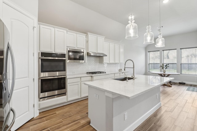 531 Campbell Dr, League City, TX 77573 - kitchen featuring stainless steel appliances, a sink, decorative backsplash, white cabinetry, and light wood-style flooring