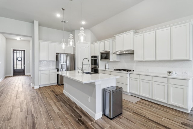 531 Campbell Dr, League City, TX 77573 - kitchen featuring appliances with stainless steel finishes, under cabinet range hood, a sink, decorative backsplash, and an island with sink
