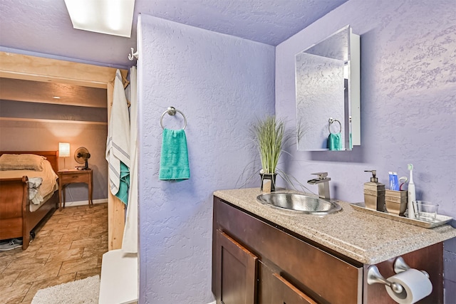 5005 Avenue N Rear Ave N, Rear, Galveston, TX 77551 - full bathroom with vanity, stone finish flooring, a textured wall, a textured ceiling, and baseboards