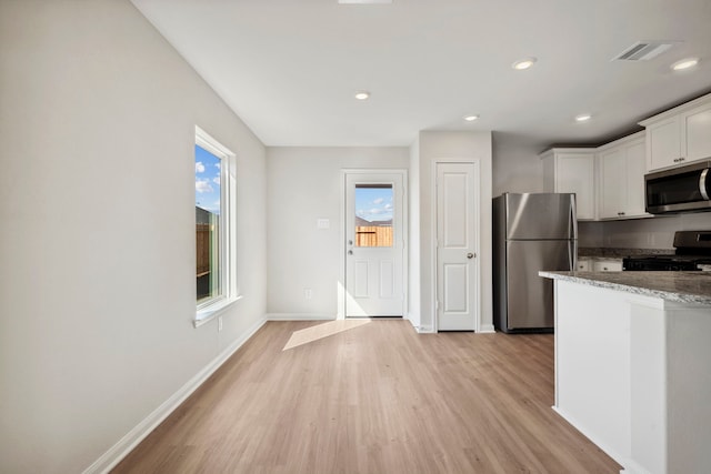 425 Tejas Trl, Waller, TX 77484 - kitchen with stainless steel appliances, light wood-type flooring, stone counters, white cabinets, and baseboards