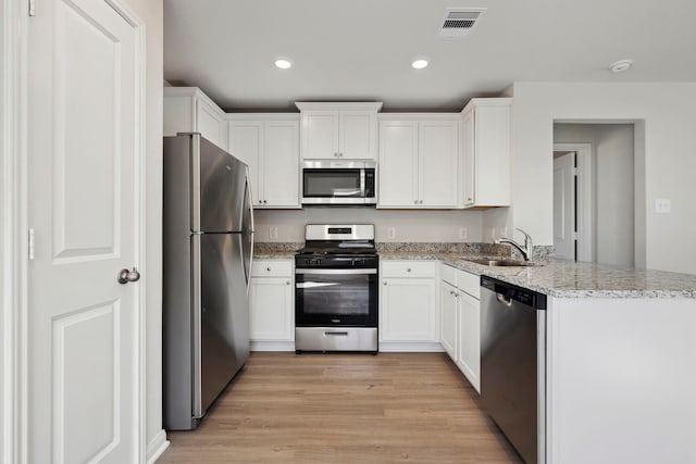 425 Tejas Trl, Waller, TX 77484 - kitchen with appliances with stainless steel finishes, a sink, white cabinets, light wood finished floors, and recessed lighting