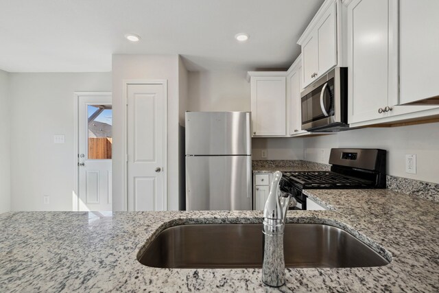 425 Tejas Trl, Waller, TX 77484 - kitchen with stainless steel appliances, a sink, light stone counters, white cabinetry, and recessed lighting
