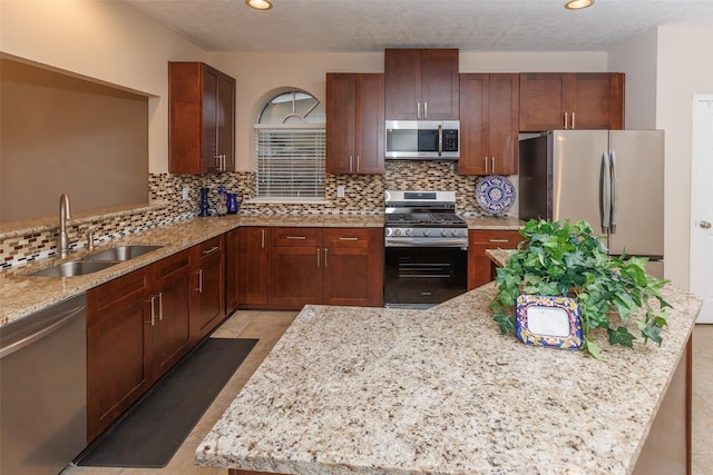 kitchen with stainless steel appliances, a sink, tasteful backsplash, light stone counters, and recessed lighting