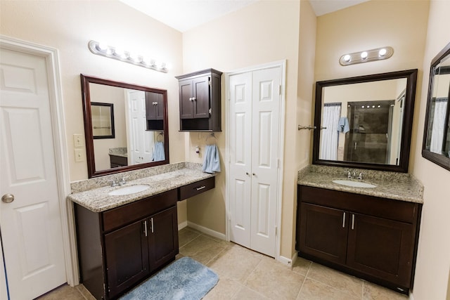 full bath with tile patterned flooring, two vanities, a shower, and baseboards