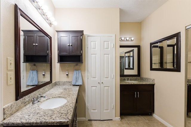 bathroom featuring two vanities, baseboards, and tile patterned flooring