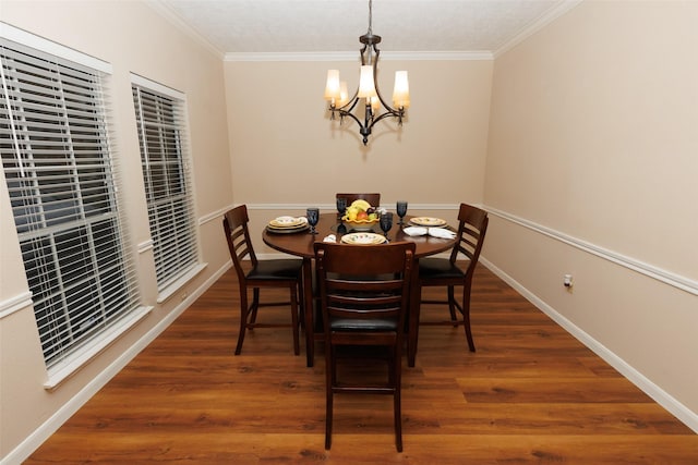 dining area featuring a chandelier, ornamental molding, wood finished floors, and baseboards