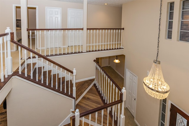 stairway with baseboards, a chandelier, and wood finished floors