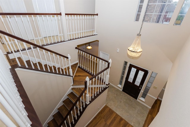 entrance foyer featuring stairway, baseboards, a towering ceiling, wood finished floors, and a chandelier