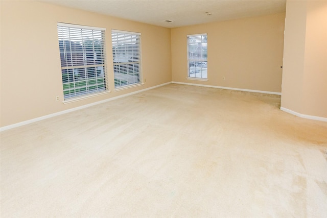 empty room featuring baseboards and light carpet
