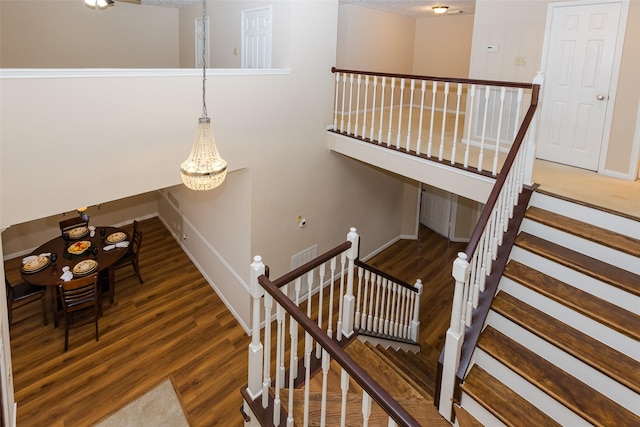 stairway with a chandelier, wood finished floors, and baseboards