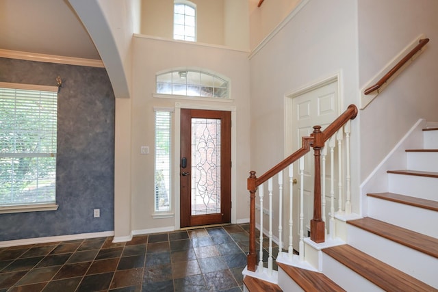 10606 Maidstone Manor Ct, Spring, TX 77379 - foyer entrance featuring arched walkways, baseboards, stone tile flooring, stairs, and a towering ceiling