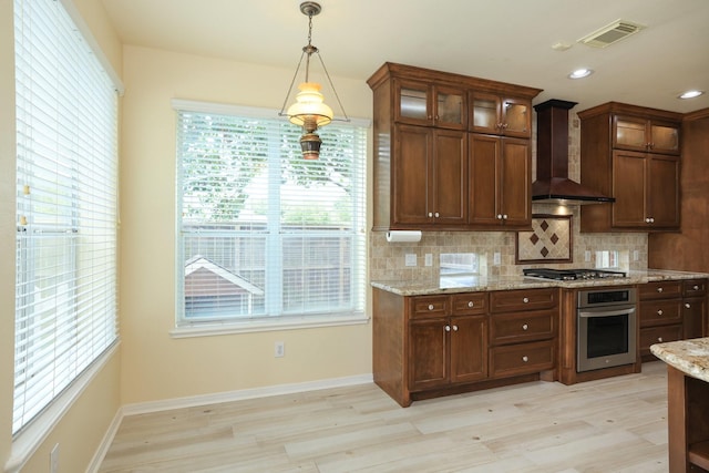 10606 Maidstone Manor Ct, Spring, TX 77379 - kitchen featuring appliances with stainless steel finishes, wall chimney range hood, light wood finished floors, backsplash, and recessed lighting