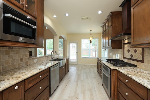 10606 Maidstone Manor Ct, Spring, TX 77379 - kitchen featuring appliances with stainless steel finishes, wall chimney exhaust hood, baseboards, recessed lighting, and light wood-style flooring