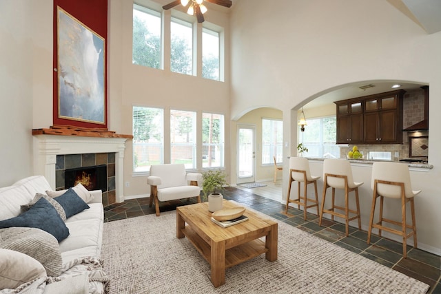10606 Maidstone Manor Ct, Spring, TX 77379 - living room with stone tile flooring, a ceiling fan, arched walkways, baseboards, and a towering ceiling