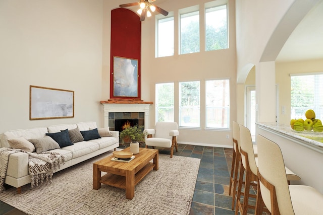 10606 Maidstone Manor Ct, Spring, TX 77379 - living area featuring stone tile flooring, arched walkways, a tiled fireplace, a towering ceiling, and ceiling fan