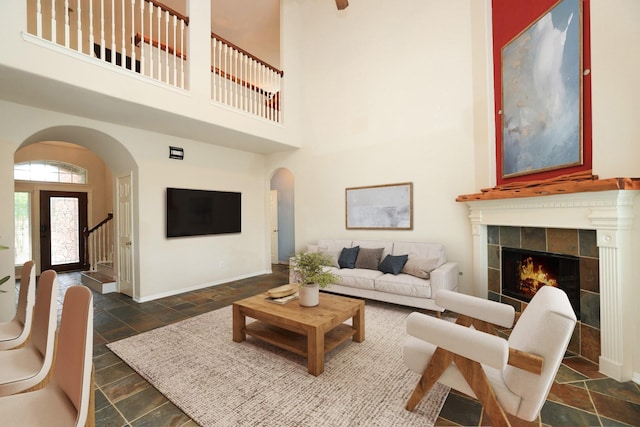10606 Maidstone Manor Ct, Spring, TX 77379 - living area with arched walkways, stone tile flooring, a high ceiling, baseboards, and a tiled fireplace