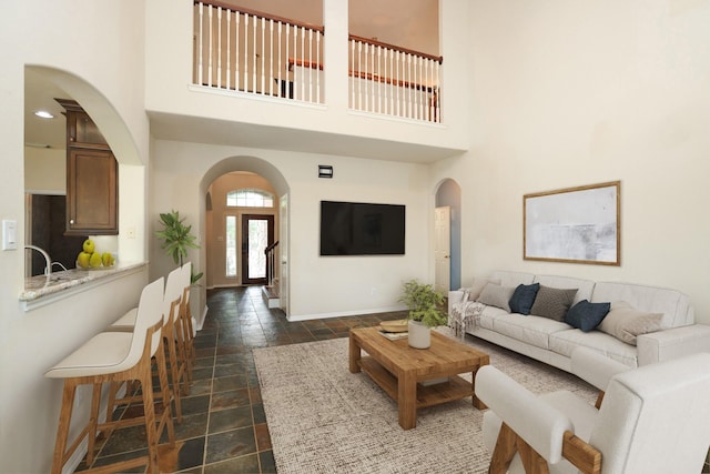 10606 Maidstone Manor Ct, Spring, TX 77379 - living room featuring arched walkways, stone tile floors, a high ceiling, and baseboards