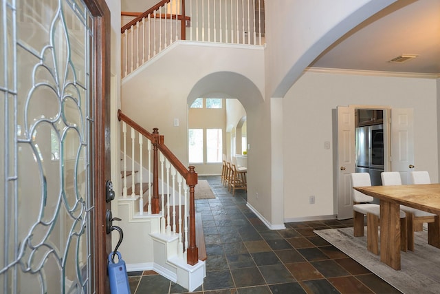 10606 Maidstone Manor Ct, Spring, TX 77379 - entrance foyer featuring arched walkways, stone tile floors, a high ceiling, stairs, and ornamental molding