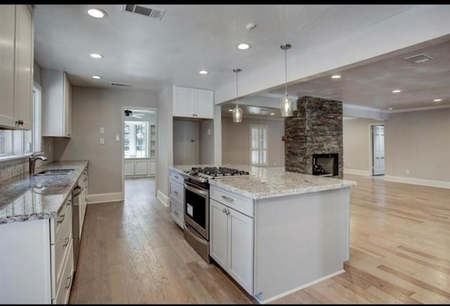 808 Chimney Rock Rd, Houston, TX 77056 - kitchen with appliances with stainless steel finishes, a sink, light wood-style floors, baseboards, and white cabinetry