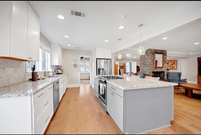 808 Chimney Rock Rd, Houston, TX 77056 - kitchen with appliances with stainless steel finishes, a stone fireplace, a center island, light wood-style flooring, and recessed lighting