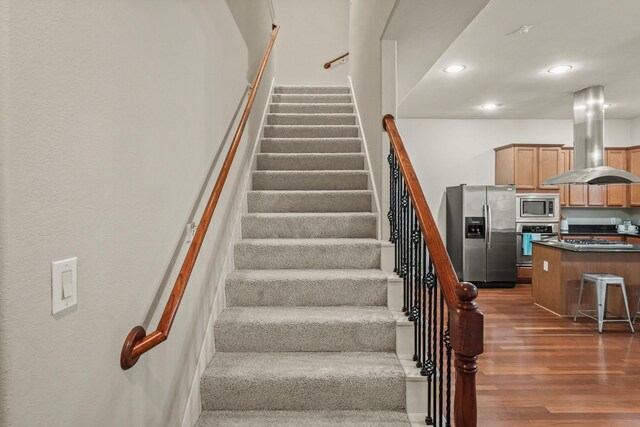 staircase featuring wood finished floors and recessed lighting