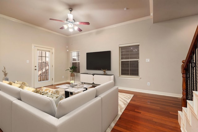 living area featuring a ceiling fan, wood finished floors, crown molding, baseboards, and stairway