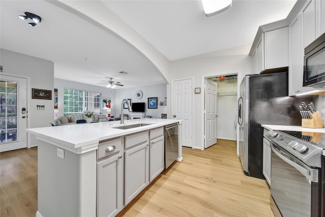 6607 Lake Woodlands Dr Unit 612, The Woodlands, TX 77382 - kitchen featuring appliances with stainless steel finishes, a sink, arched walkways, ceiling fan, and a kitchen island with sink