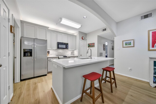 6607 Lake Woodlands Dr Unit 612, The Woodlands, TX 77382 - kitchen featuring stainless steel appliances, a sink, arched walkways, light wood finished floors, and backsplash