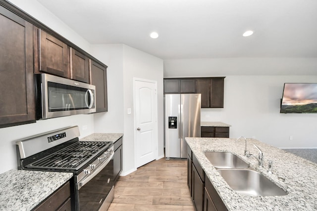 4727 Lombardy Fire Trl, Katy, TX 77449 - kitchen featuring stainless steel appliances, a sink, dark brown cabinetry, light wood-style flooring, and light stone counters