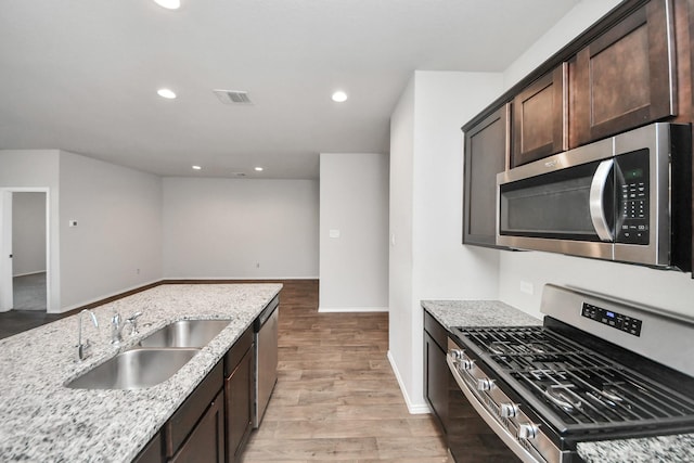 4727 Lombardy Fire Trl, Katy, TX 77449 - kitchen featuring appliances with stainless steel finishes, a sink, dark brown cabinetry, light stone counters, and recessed lighting