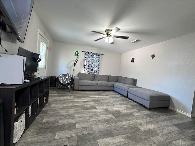 living area with a ceiling fan, wood finished floors, and baseboards