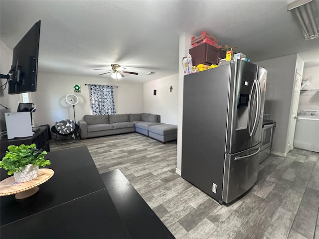 kitchen with stainless steel appliances, washer / clothes dryer, light wood-type flooring, a ceiling fan, and baseboards