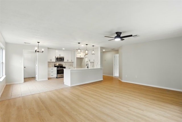 5318 Cilantro Ln, Baytown, TX 77521 - unfurnished living room featuring light wood finished floors, baseboards, ceiling fan, a chandelier, and a sink