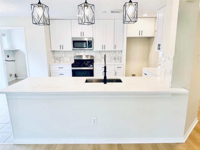 5318 Cilantro Ln, Baytown, TX 77521 - kitchen with stainless steel appliances, a sink, backsplash, light stone countertops, and white cabinetry