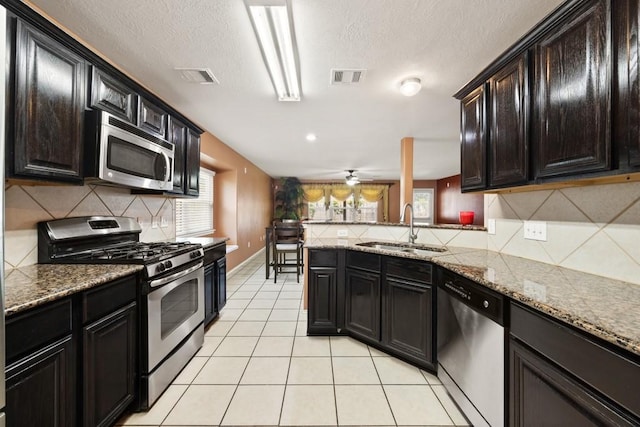 6818 Whitbourne Meadow Ln, Houston, TX 77040 - kitchen with appliances with stainless steel finishes, a sink, tasteful backsplash, light tile patterned floors, and light stone countertops