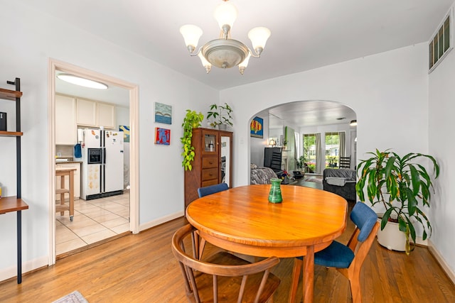 863 W 43rd St, Houston, TX 77018 - dining area with arched walkways, a chandelier, light wood-style floors, and baseboards