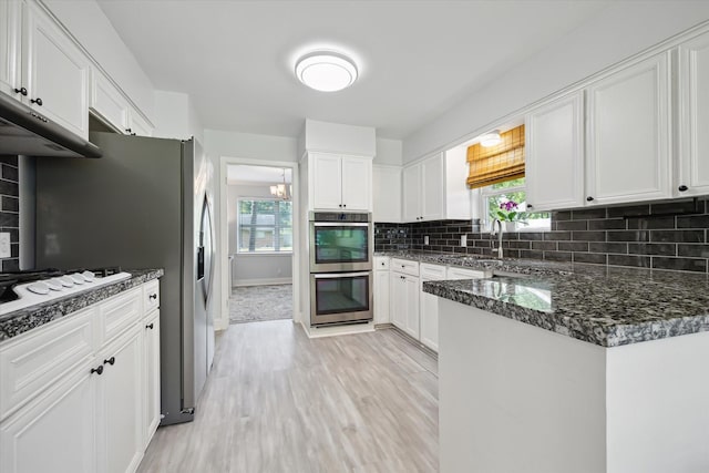 5402 Indigo St, Houston, TX 77096 - kitchen with double oven, white cabinets, light wood finished floors, and backsplash