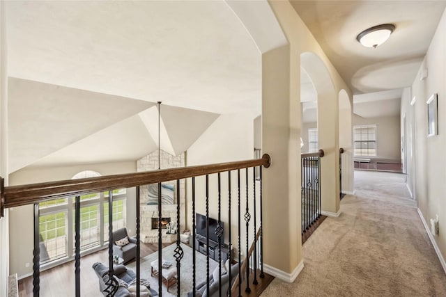 hall featuring arched walkways, baseboards, carpet floors, and lofted ceiling