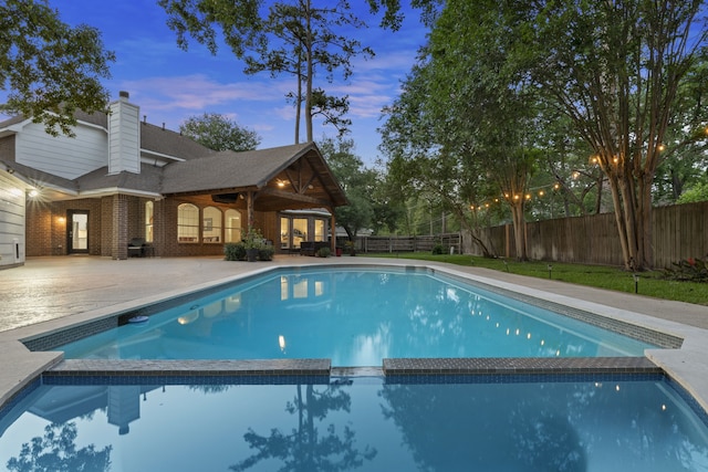 6503 Ambercrest Ct, Spring, TX 77389 - pool at dusk featuring a pool with connected hot tub, a fenced backyard, and a patio area