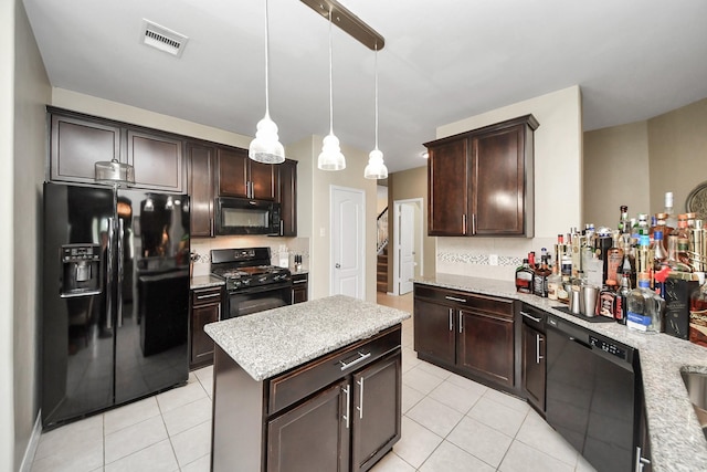 9703 Tipton Sands Dr, Humble, TX 77396 - kitchen featuring black appliances, light tile patterned floors, dark brown cabinetry, hanging light fixtures, and light stone counters