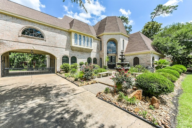 3230 Ivy Falls Dr, Houston, TX 77068 - french country inspired facade with brick siding, roof with shingles, and concrete driveway