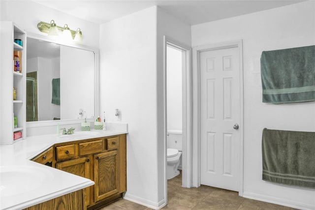 full bathroom with toilet, vanity, a shower with door, baseboards, and tile patterned flooring