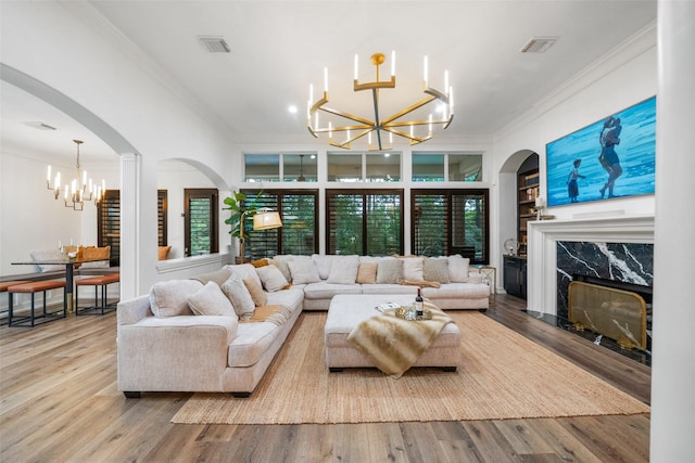 1924 Boulder Ridge Dr, Conroe, TX 77304 - living area featuring a chandelier, ornamental molding, a fireplace, arched walkways, and wood finished floors